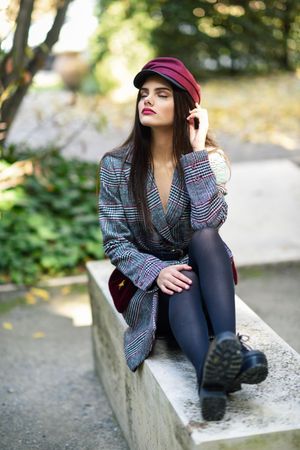 Female in warm winter clothes sitting on park stoop with her eyes closed