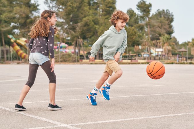 Content teen boy and girl playing basketball in city
