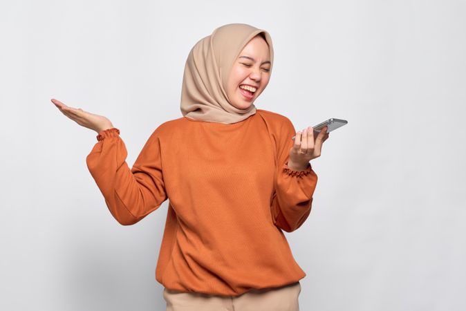 Happy Muslim woman smiling talking on smart phone speaker