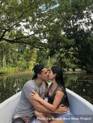 Man and woman kissing while sitting in boat in river surrounded by tree 5zPdXb