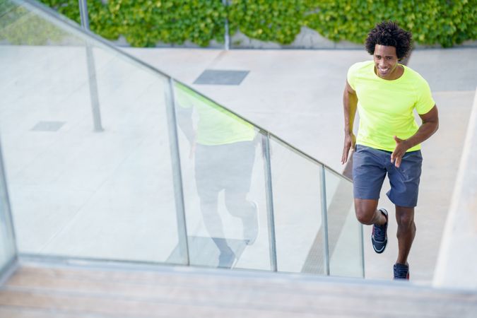 Man in neon T-shirt running up steps outside