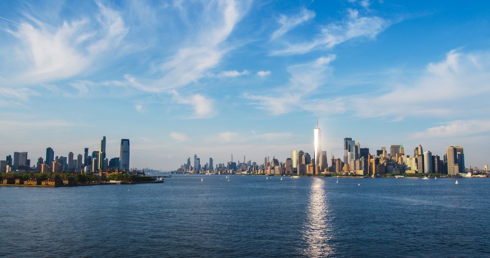 Aerial Photo with Manhattan Island with Office and Apartment Buildings. Hudson River Scenery with Yachts, Boats, and Sun Reflecting From the One World Trade Center Skyscraper