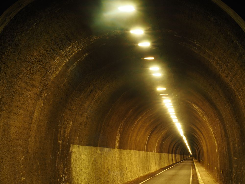 Empty concrete tunnel with road in lamplight