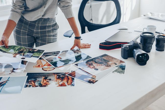 Female photographer looking at photo prints on white office desk