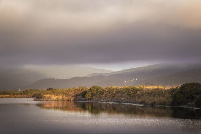 Dark clouds accumulating over still body of water