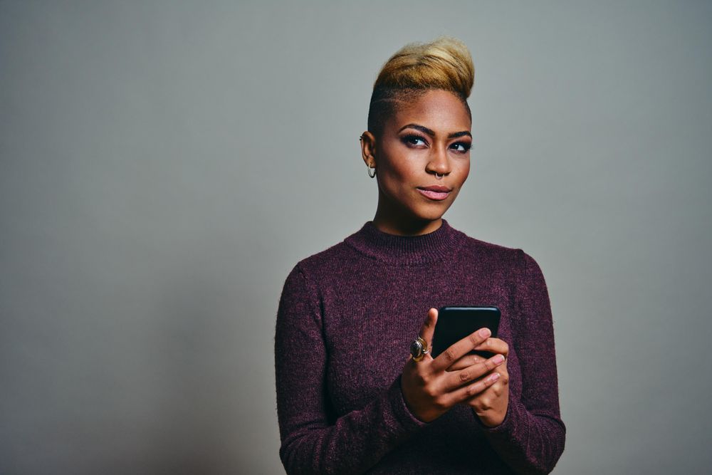 Black woman thinking about a text on a cell phone