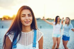 Portrait of smiling brunette woman with friends in background on beach