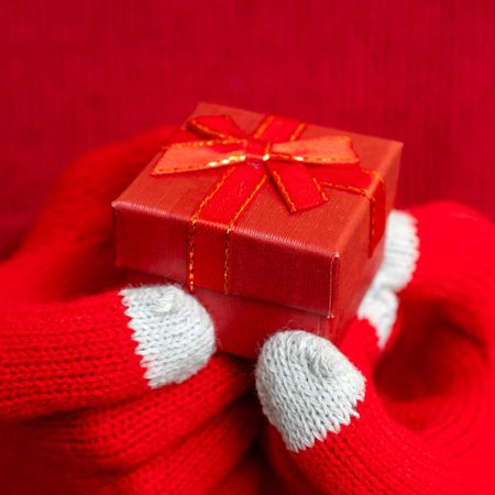 Hands with red gloves holding gift box