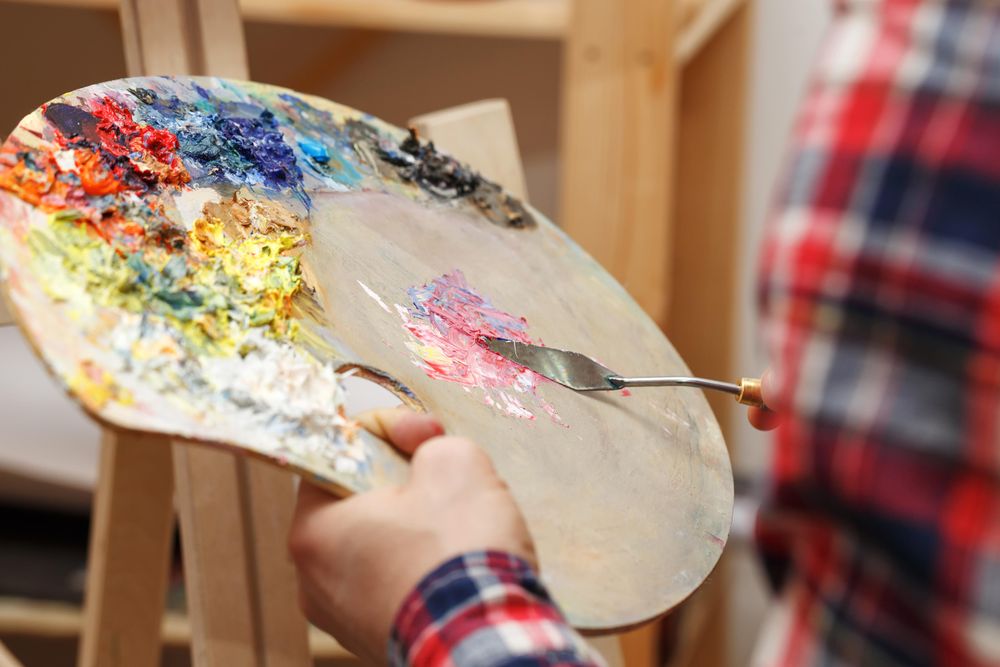 Person in plaid shirt mixing oil paints on palette