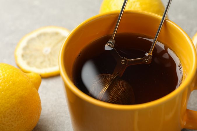 Cup of tea and lemons on grey background, closeup