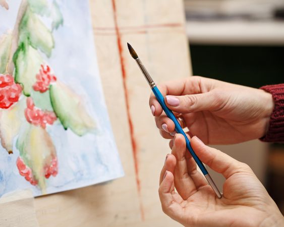 Teacher showing student a paintbrush technique
