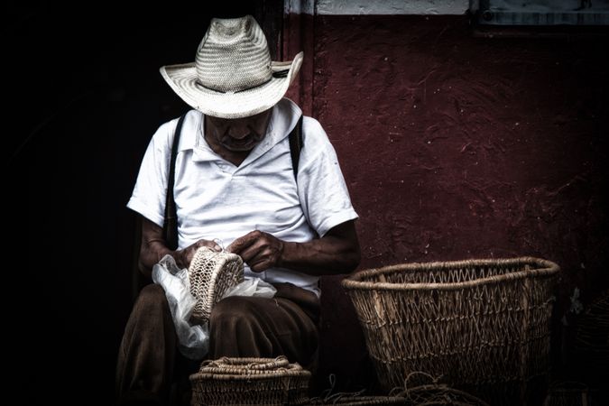 Older man weaving wicker basket