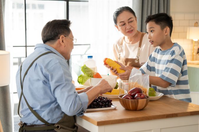 Asian grandparents support and help grandson cooking breakfast in the kitchen