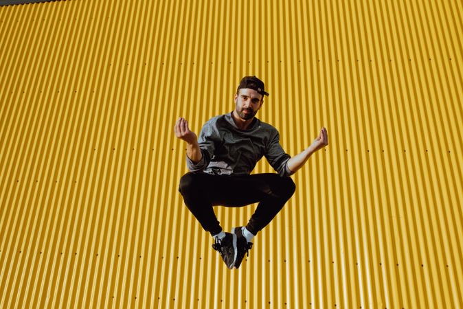 Man jumping near yellow wall