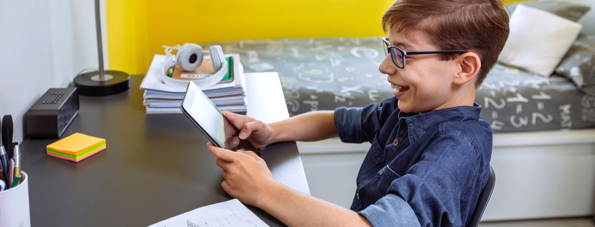 Happy preteen doing homework with a tablet