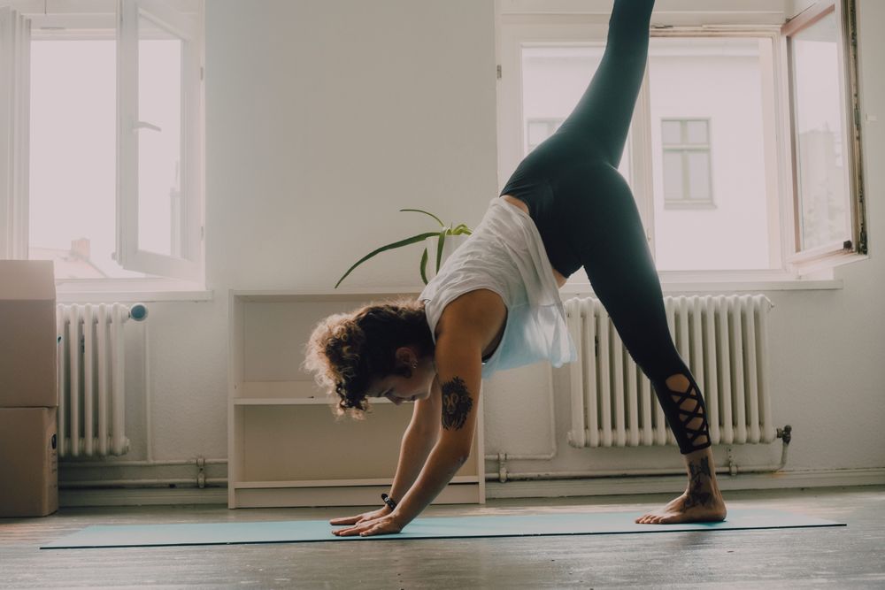 Calm woman practicing yoga pose and balancing on hands at home