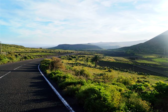 Endless road riding to mountains along fields