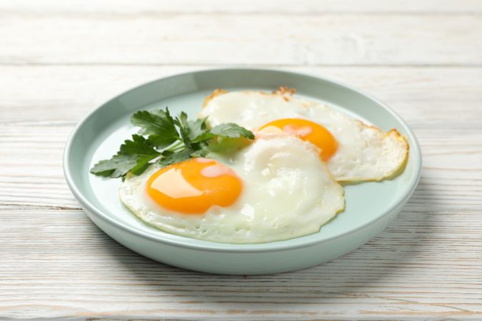 Two eggs sunny side up on blue plate