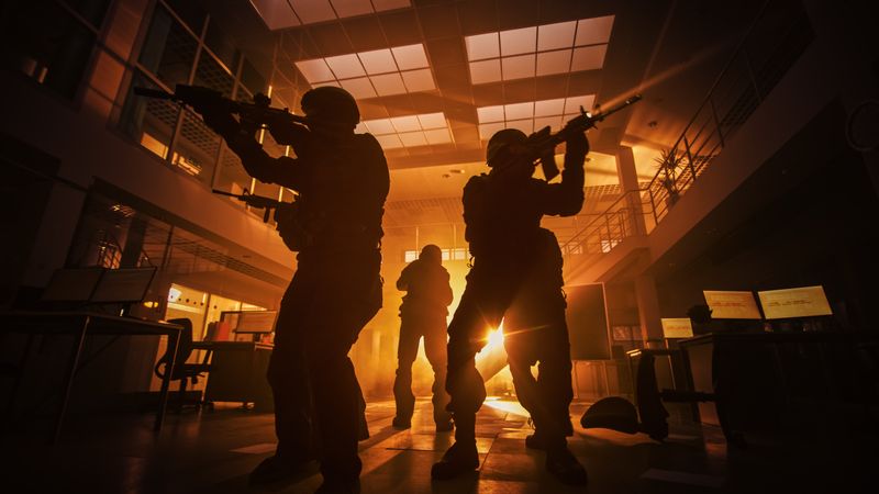Masked Squad of Armed SWAT Police Officers Move in a Hall of a Dark Seized Office Building with Desks and Computers.