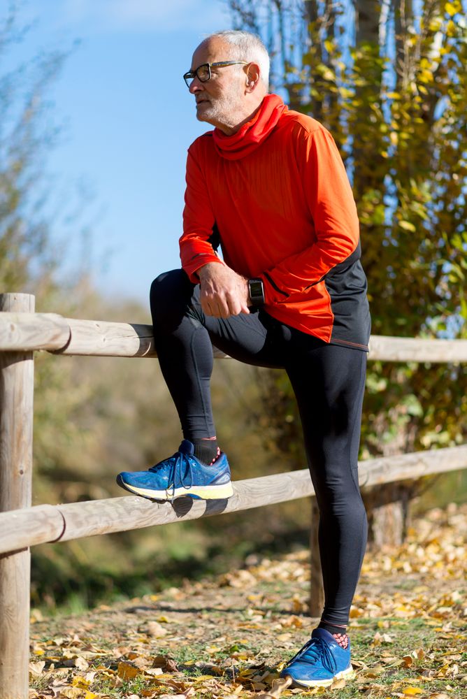 Older male leaning with leg up on wooden fence