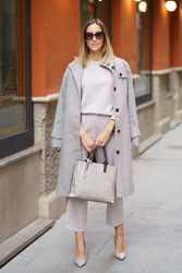 Chic woman in grey standing outside with bag