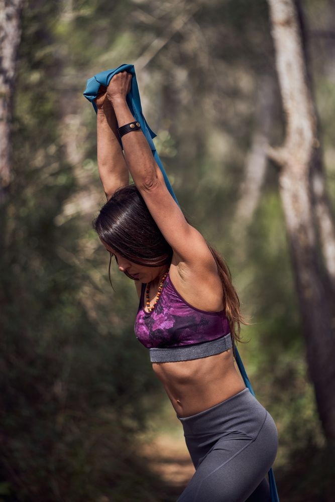 Strong female athlete doing triceps exercise with ribbon