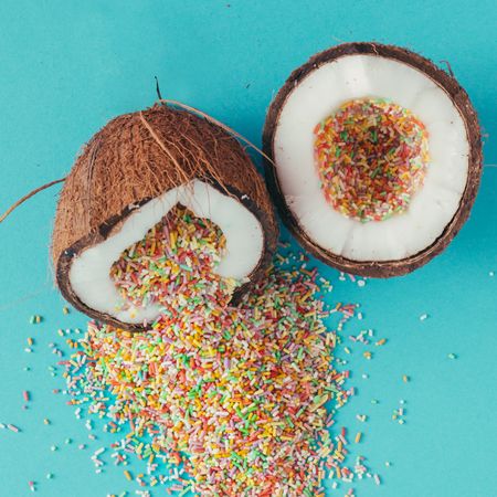 Coconut halves full of colorful sprinklers on blue background