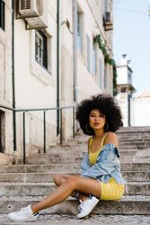 Stylish female sitting in stairs with railing outdoors