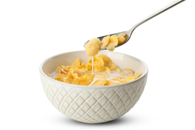 Spoon and bowl of muesli with milk isolated on plain background