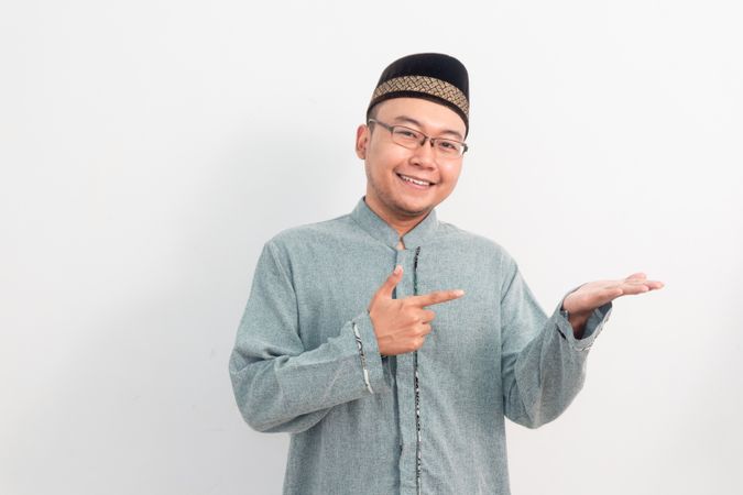 Asian Muslim man smiling showing product gesture in Ramadan