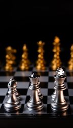 Silver chess pieces against golden rivals