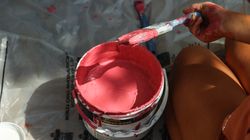 Cropped image of a hand holding paint brush beside a pink painting 0yMwL0
