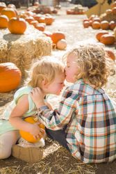 Sweet Little Boy Kisses His Baby Sister at Pumpkin Patch.
