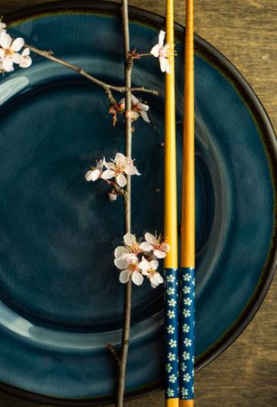 Table setting with chop sticks on ceramic navy plate and cherry blossom branch