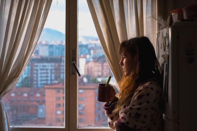Woman enjoying hot beverage near fridge