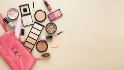 Beauty bag with facial powders and eye shadows on table
