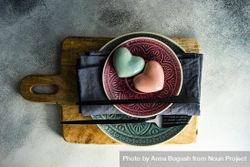 Ornate plates with pastel ceramic heart on cutting board 0KMMm1