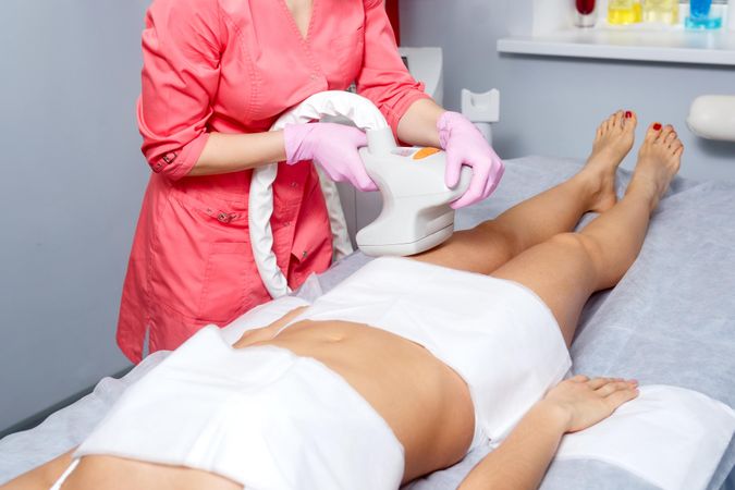 Cosmetologist doing beauty treatment on client’s leg