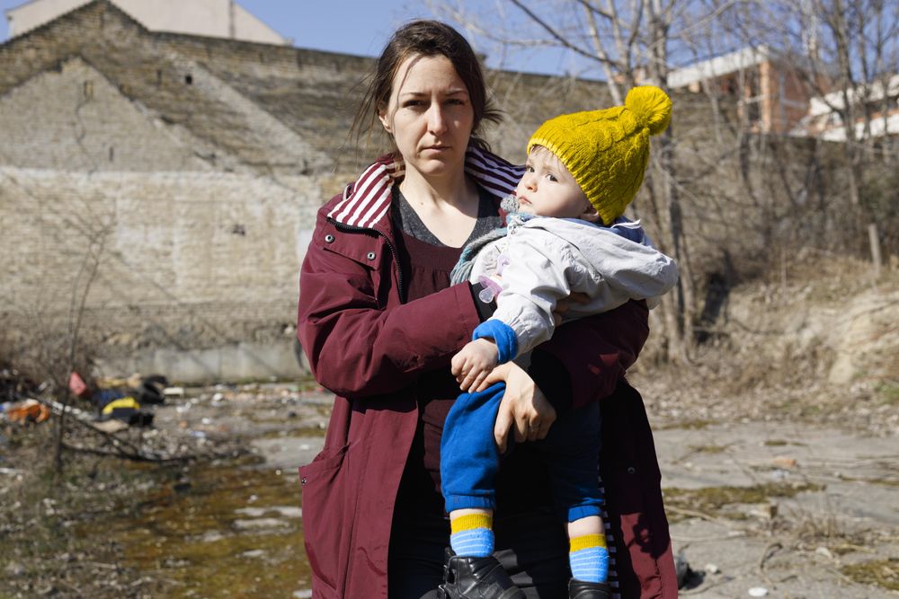 A woman standing with her child among the ruins