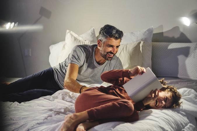 Father tickling son on bed