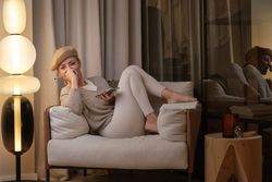 Content woman with smartphone sitting in armchair