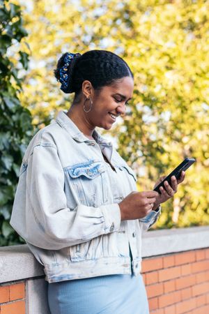 Black Latina woman using a smartphone in the park on a summer day.