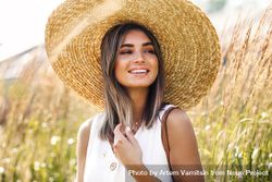 Smiling woman in sunhat enjoying a sunny day in the field 5nnQ65