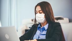 Woman in business attire sitting in front of her computer at work