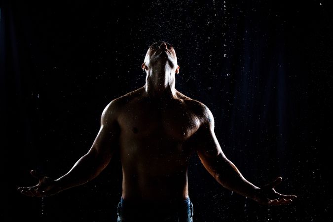 Muscular male under rain