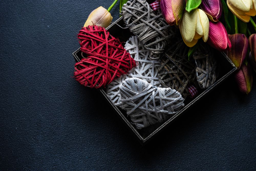 Box of thatched heart ornaments surrounded by fresh tulip flowers