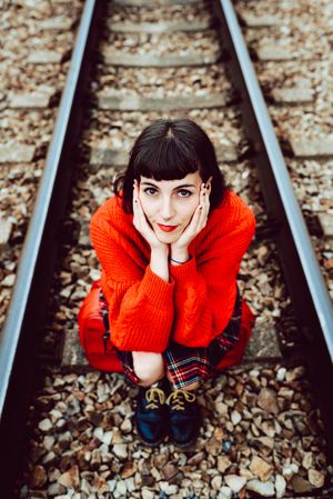 Woman sitting on sleepers in middle of railway