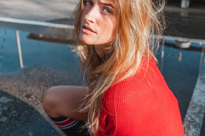 Charming woman in sweater on street between puddles