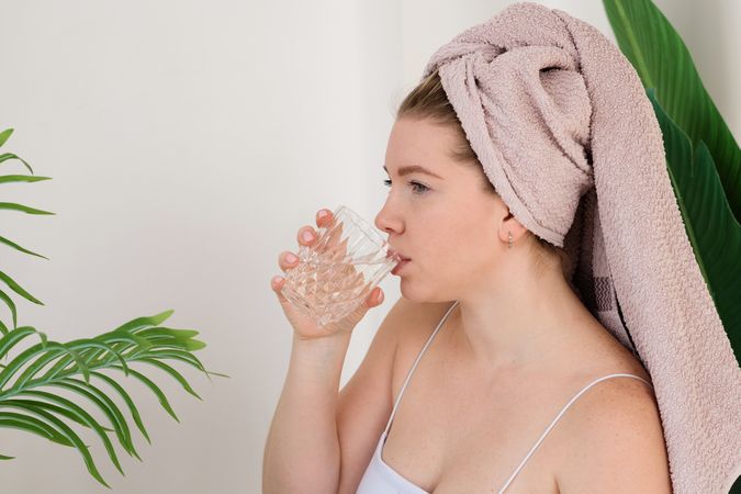 Woman drinking water after skincare.