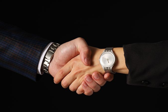 Male handshake close-up on a dark background